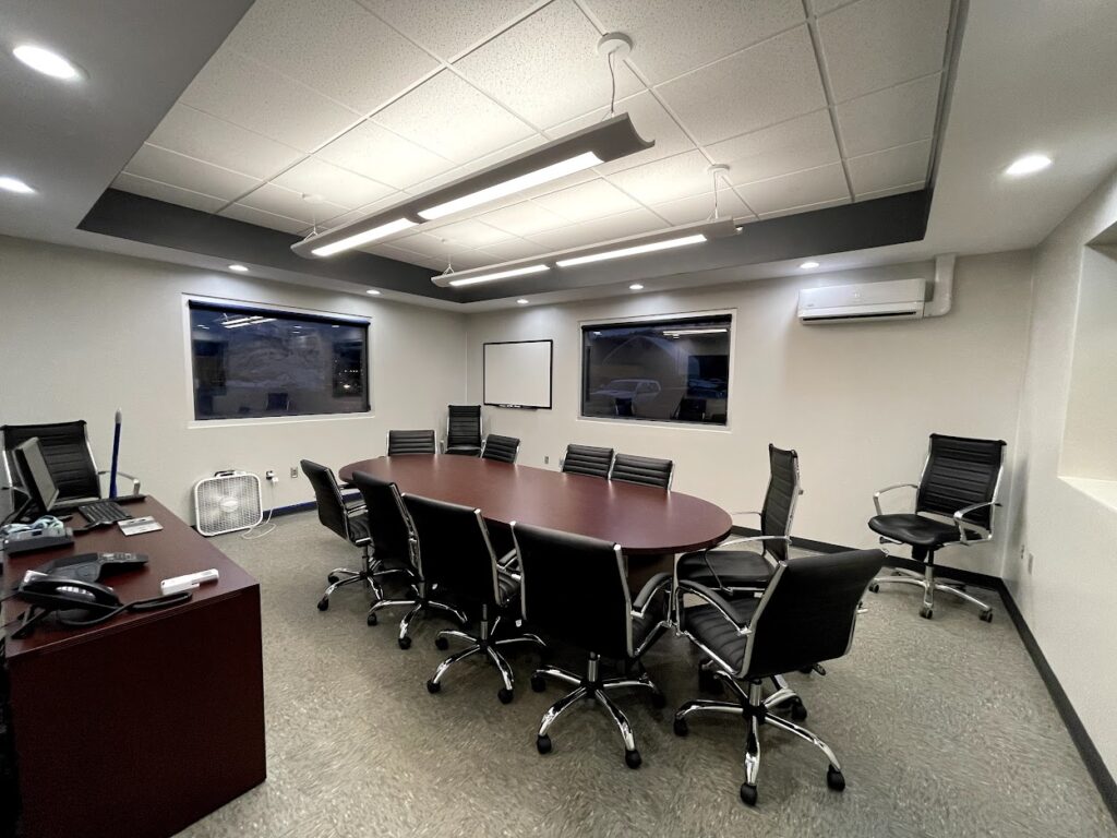 Small meeting room with wooden table and rolling chairs.
