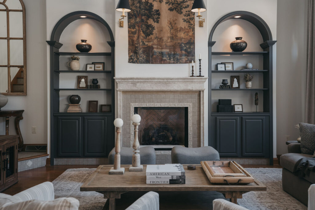 Black-painted arched shelving units with cream walls, fireplace, and decorative accent lighting in residential living room