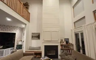 Cream-painted two-story residential living room with white shiplap fireplace surround, black fireplace insert, recessed how to prep a room for painting