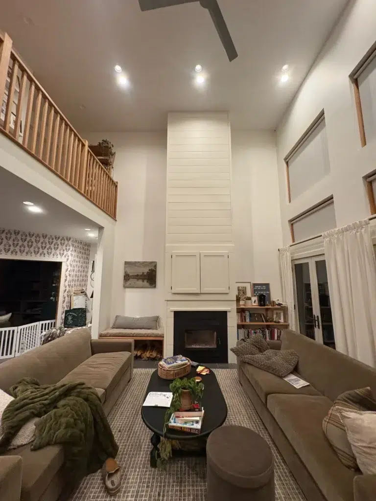 Cream Living Room Fireplace Cream-painted two-story residential living room with white shiplap fireplace surround, black fireplace insert, recessed